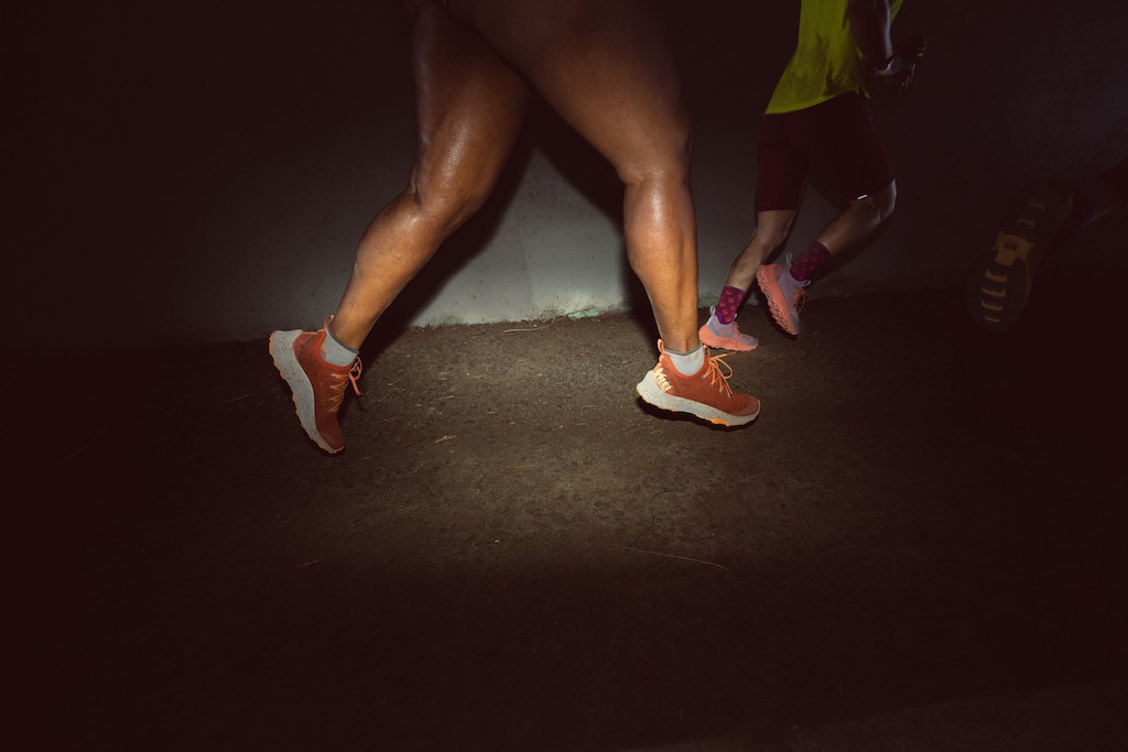 From the legs down, a person running in the Swiftland MT trail running shoes in the colorway Deep Orange. 