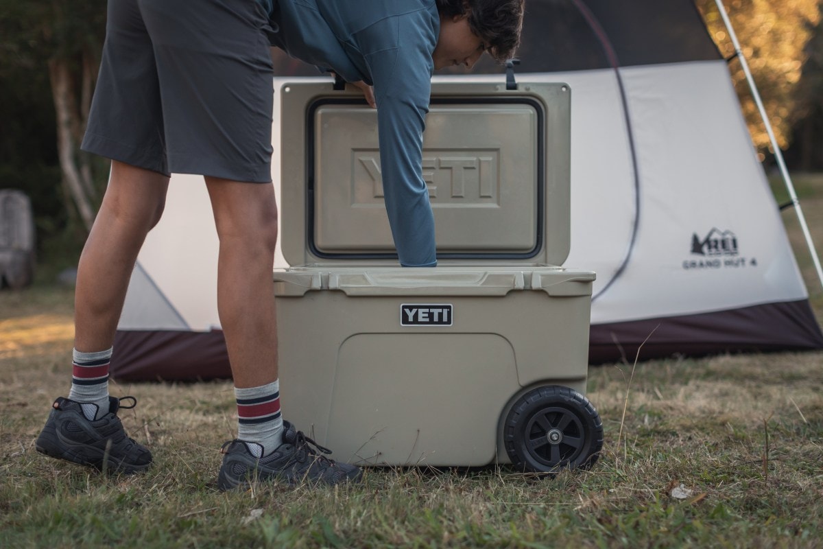 A young guy reaches into an open cooler at camp.