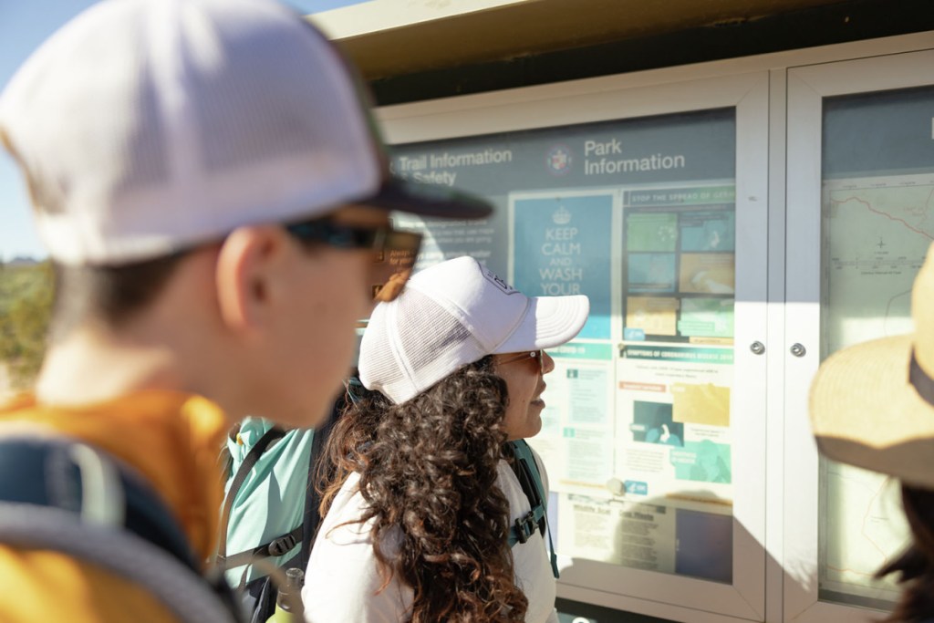 Two hikers consult the trail map at a park.