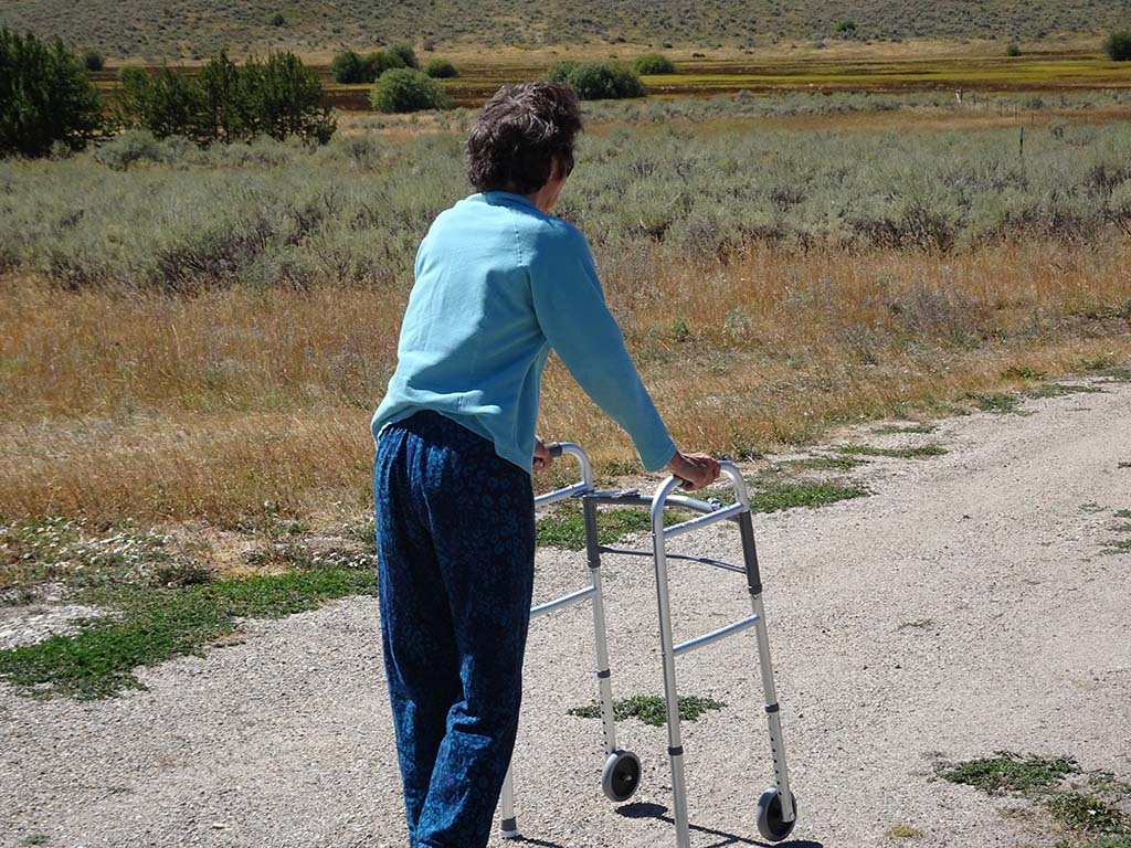 A person on a gravel trail using a walking assistance device.
