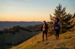 Two hikers walk on a ridge at daybreak