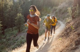 Three people running on a mountain trail, as if towards the camera.