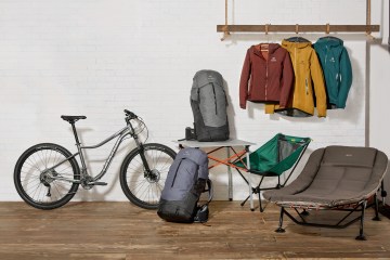 Editorial photo of various gear, including a bike, jackets and two packs.