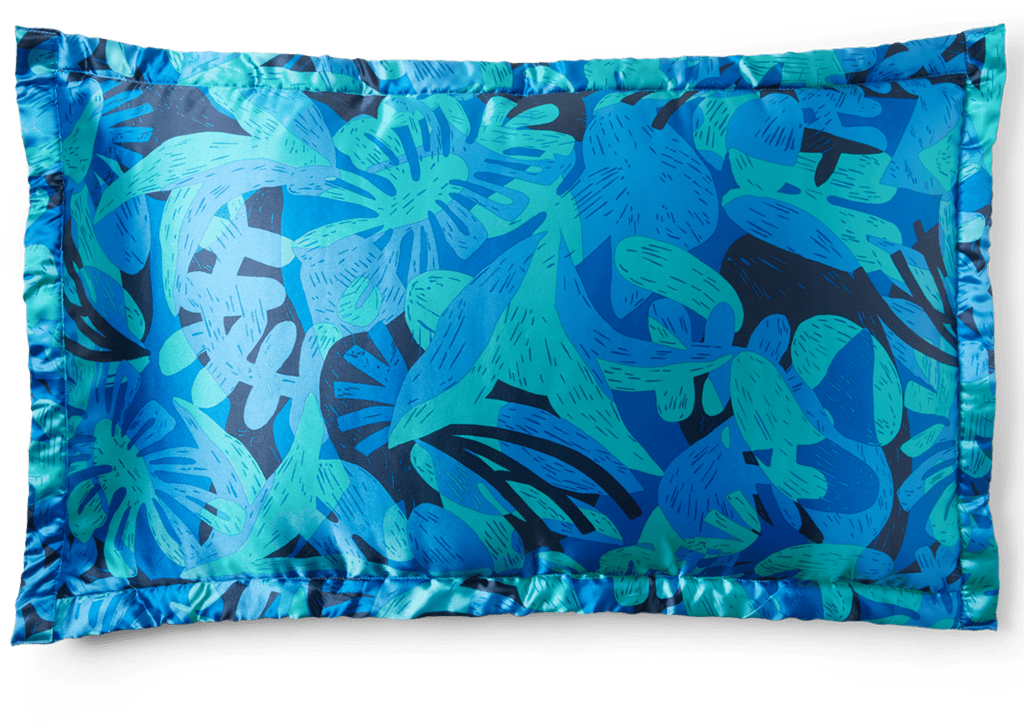 A satin pillow featuring organic shapes in a variety of blues and blue-greens.