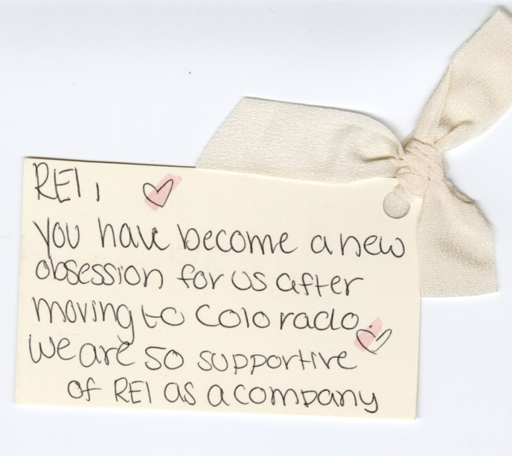 A handwritten card with drawn hearts, embellished with a decorative bow