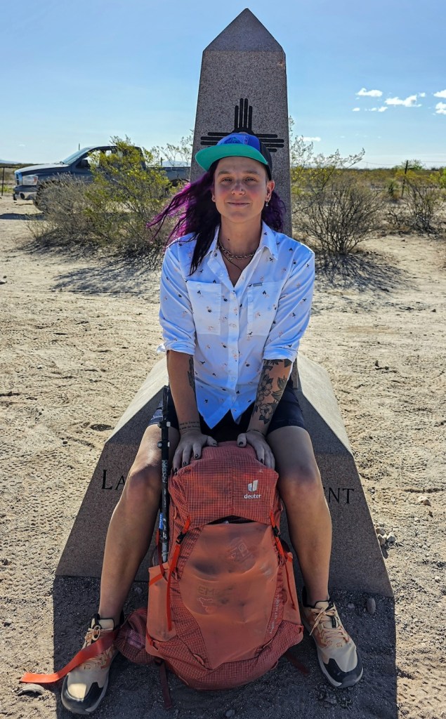 Lyla Harrod sits in front of a statue with an orange backpack.