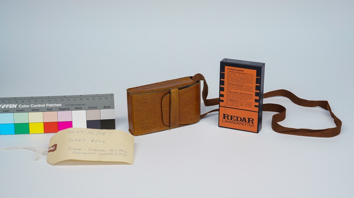 A picture of an old avalanche locator next to its leather case.