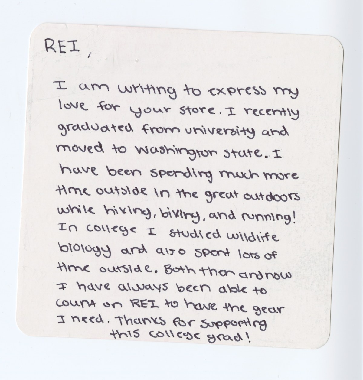 A handwritten note on a small square notecard with rounded edges