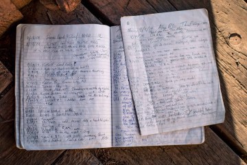 A notebook open along its spine, filled with hiker logs from the PCT.
