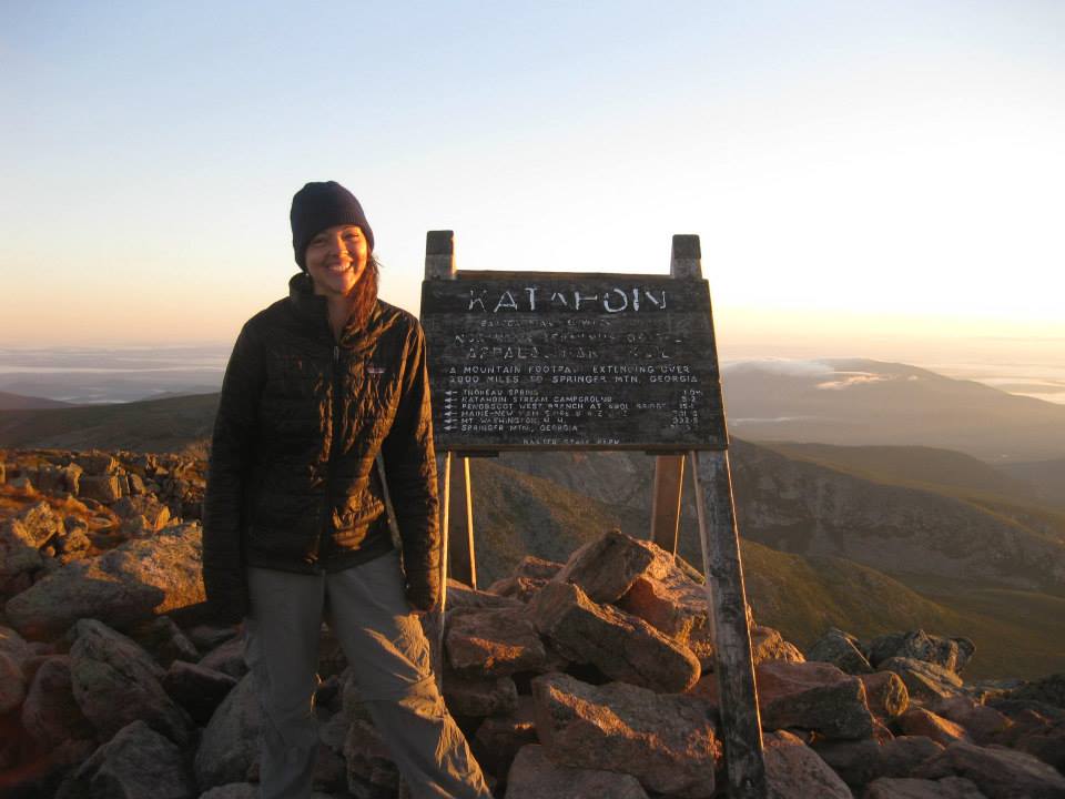 A hiker poses by a trail marker on the Appalachian trail.