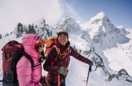 Two women laugh below Buck Peak in a snowy Grand Teton National Park