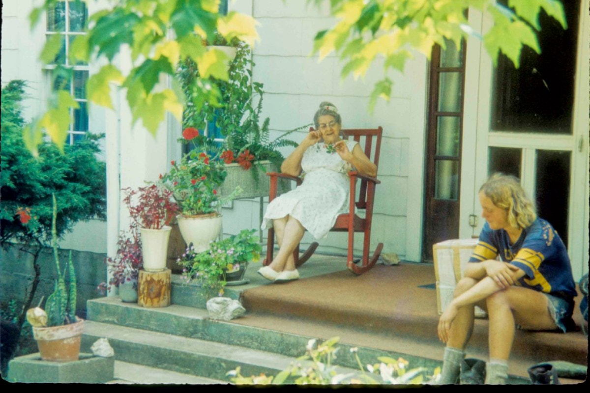 Two people sit on a porch in an old photograph