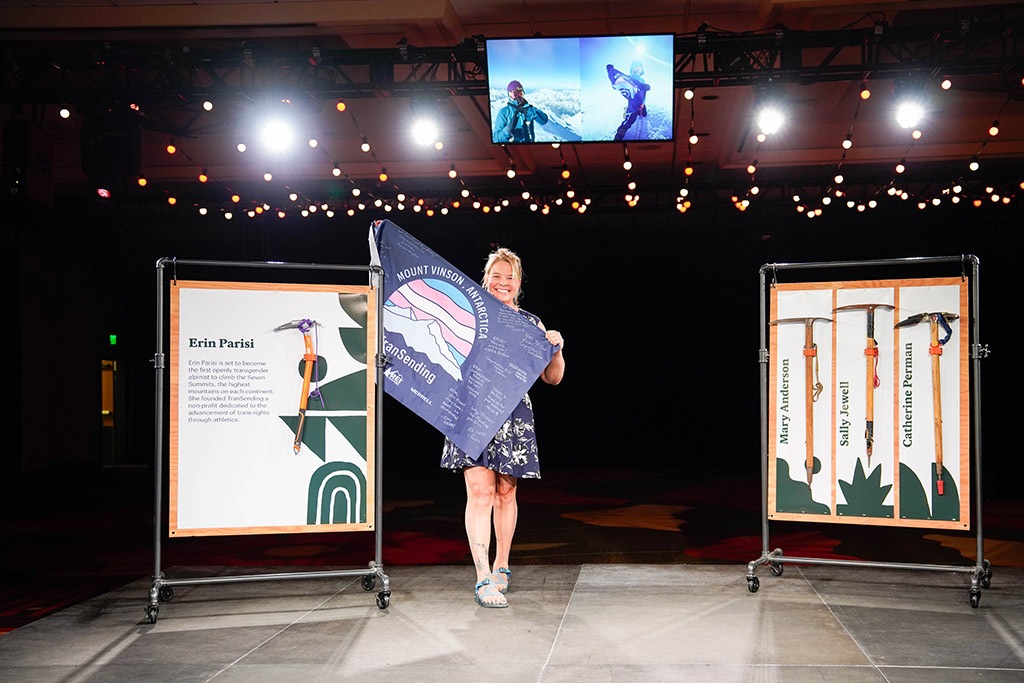 Erin Parisi stands next to her ice axe an unfurls the Transcending flag she shows at the top of each mountain she summits