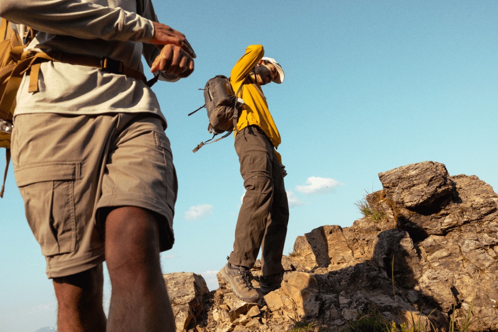 Two people stand at the top of a rocky outcropping.