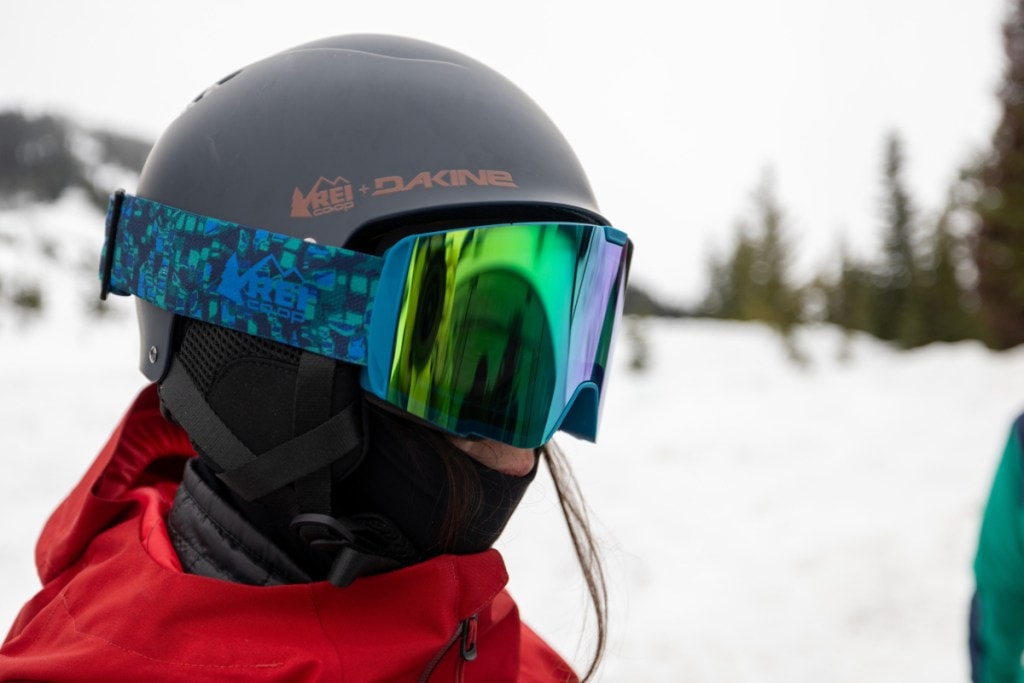 A skier wears a blue tinted pair of snow goggles with a helmet