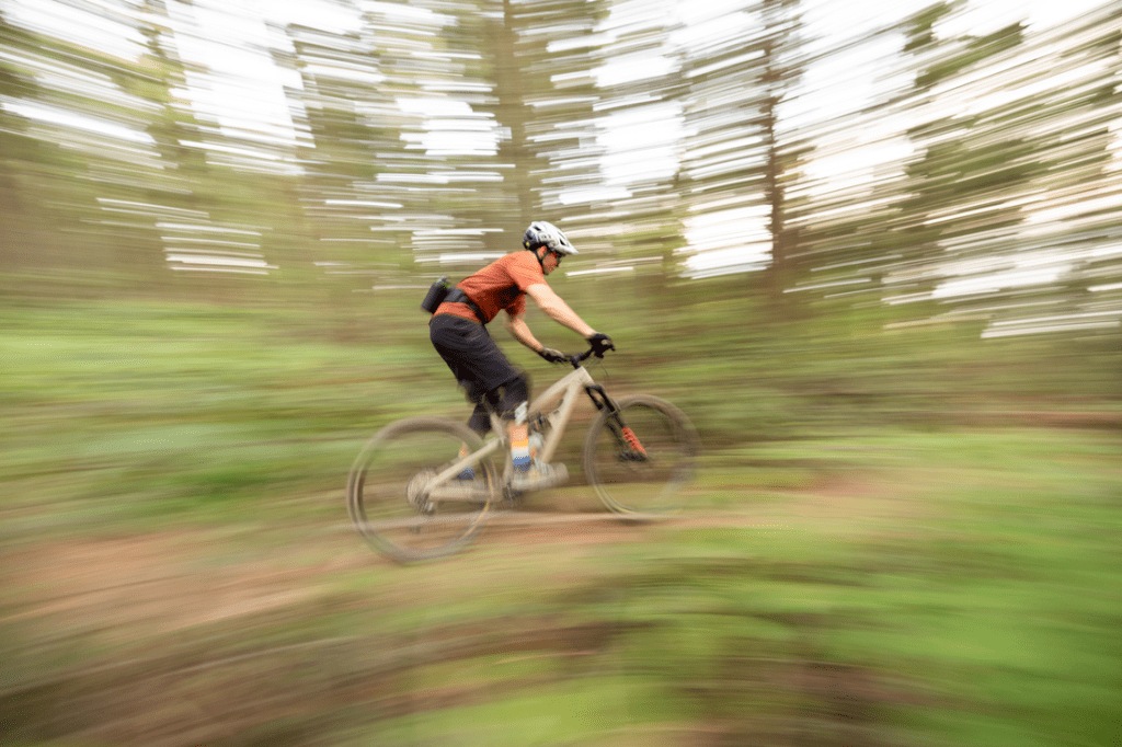 A mountain biker zooming through the woods on a trail