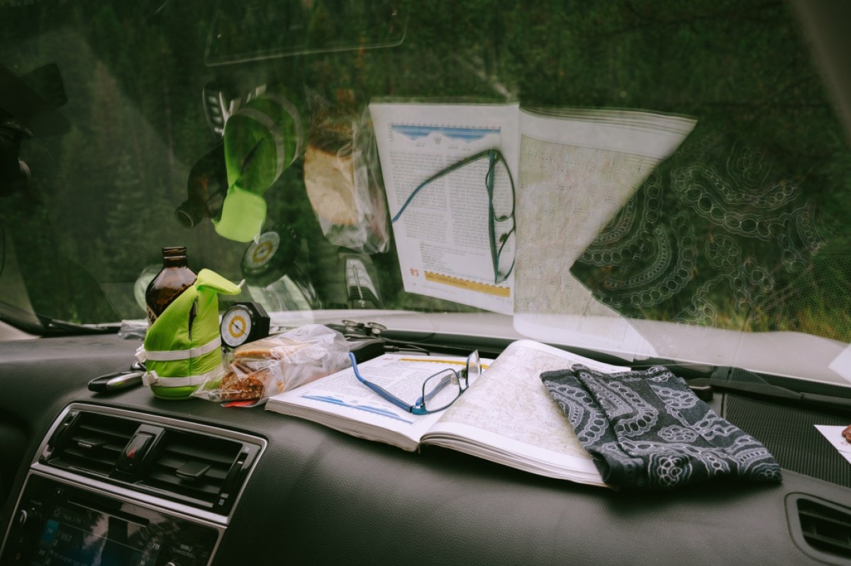 A photo of maps and hiking items on the dashboard of a car