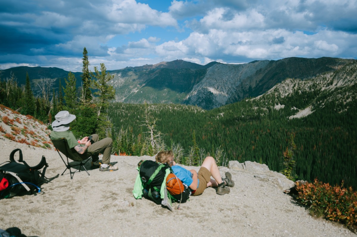 Two backpackers relax on the rock cliff, viewing the mountain scenery