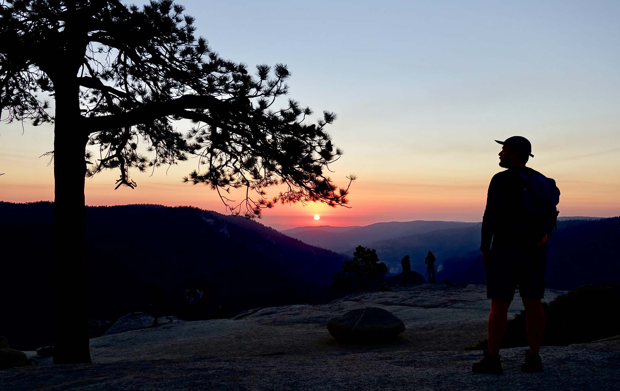 A person in silhouette watches a sunset