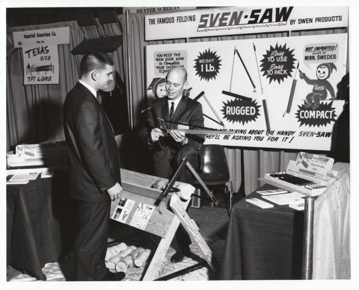 Two people standing at a trade show in front of a Sven-Saw sign