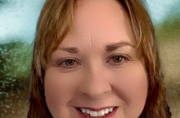 A close-up of a person in a blue shirt smiling at the camera