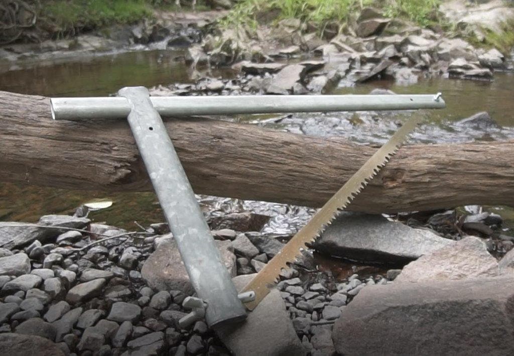 An early prototype of the Sven-Saw leaning on a log outdoors