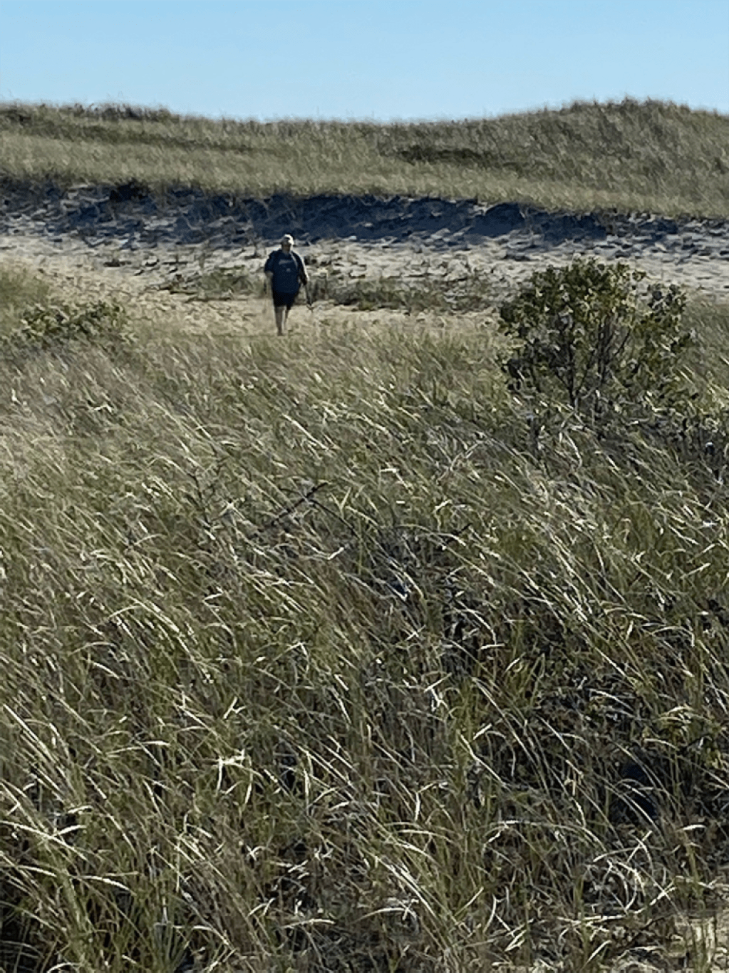 A person in the distance walks alone using trekking poles