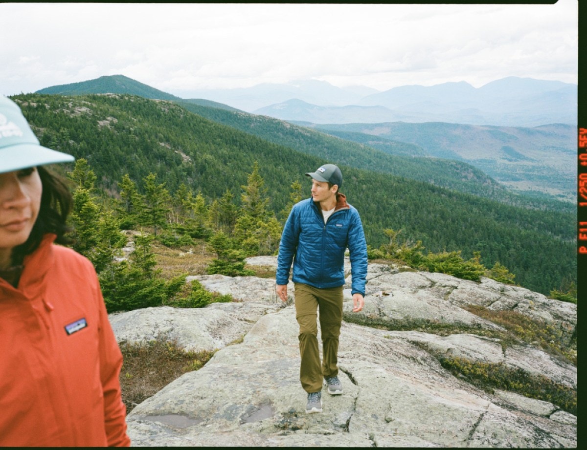 A person in an orange Patagonia fleece is in the foreground and a person in the middle ground is on a boulder.