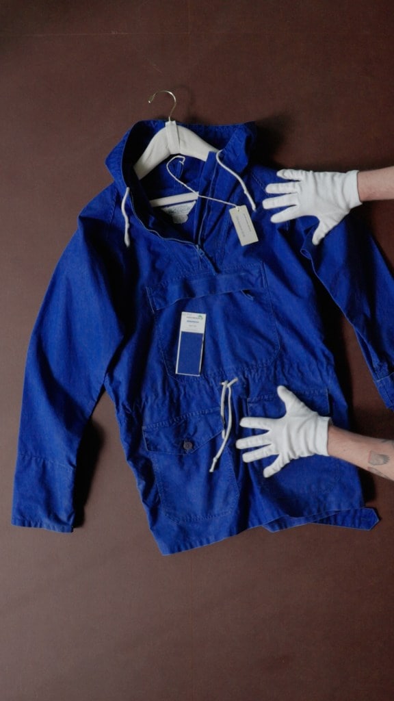Two gloved hands hold a bright blue anorak jacket.