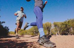 Two people running on a trail in the HOKA Challenger 8 trail-running shoes in black.