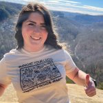 A person standing on a rock and giving a thumbs up sign, smiling at the camera