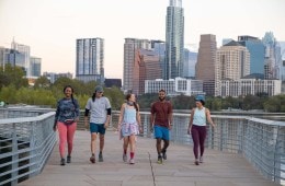 Five people walk along a paved path in an urban landscape