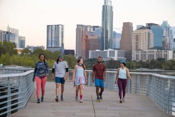 Five people walk along a paved path in an urban landscape