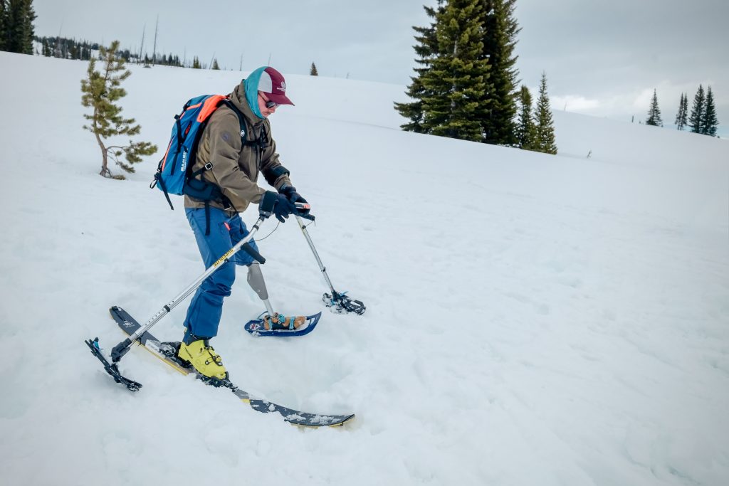 A person with a prosthetic leg skis down a snowy moutain