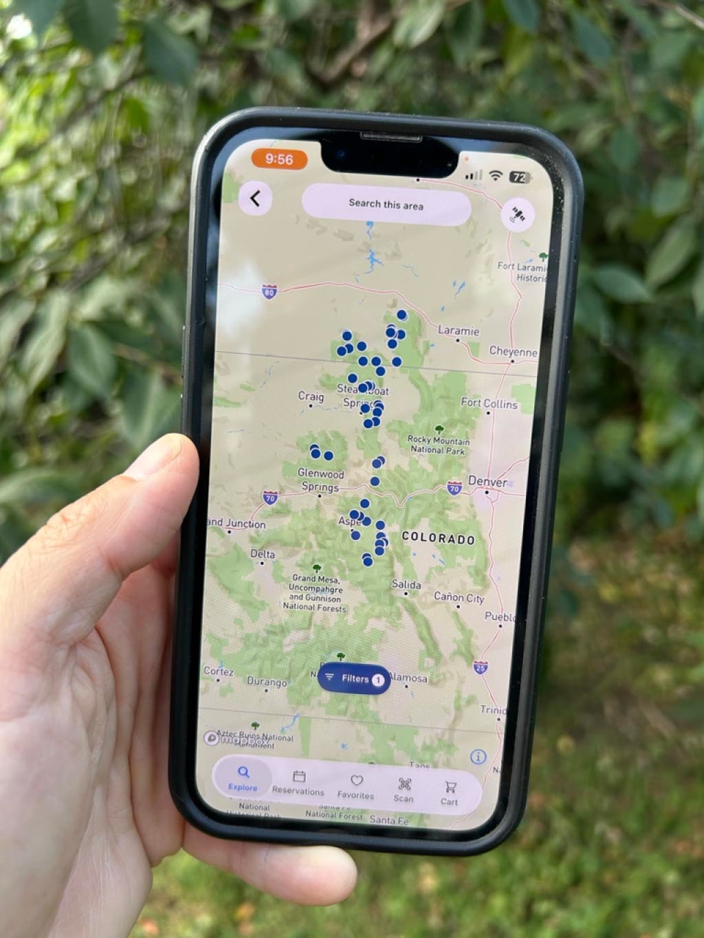 A person holds a phone displaying the Recreation.gov app, showing available campsites