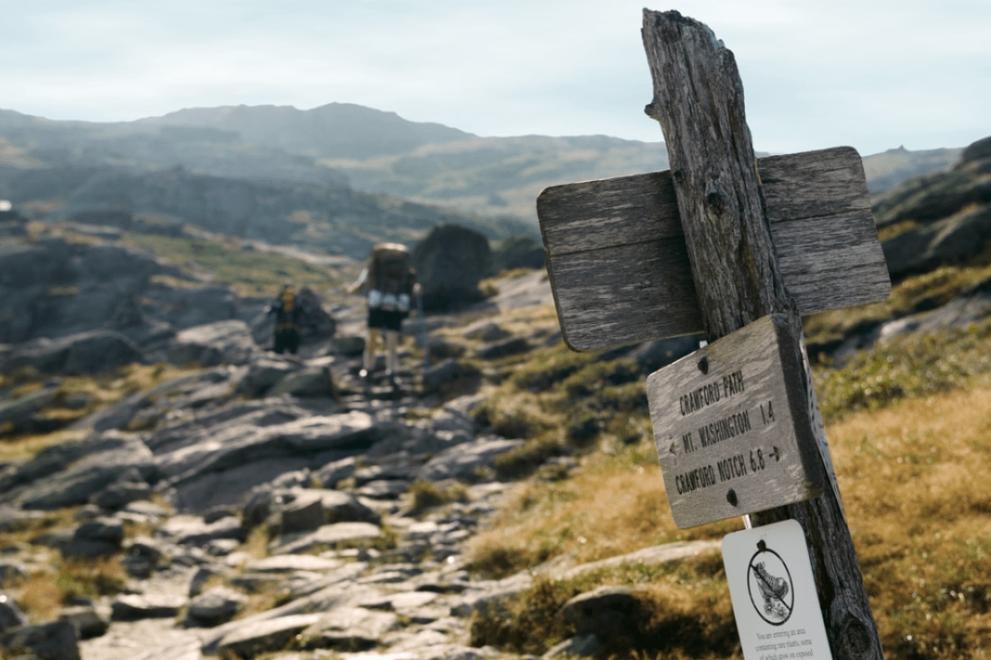 A signpost on the Appalachian Trail, indicating that this trail segment is called Crawford Path and Mount Washington is about 1.4 miles in one direction and Crawford Notch is 6.8 miles in the other.