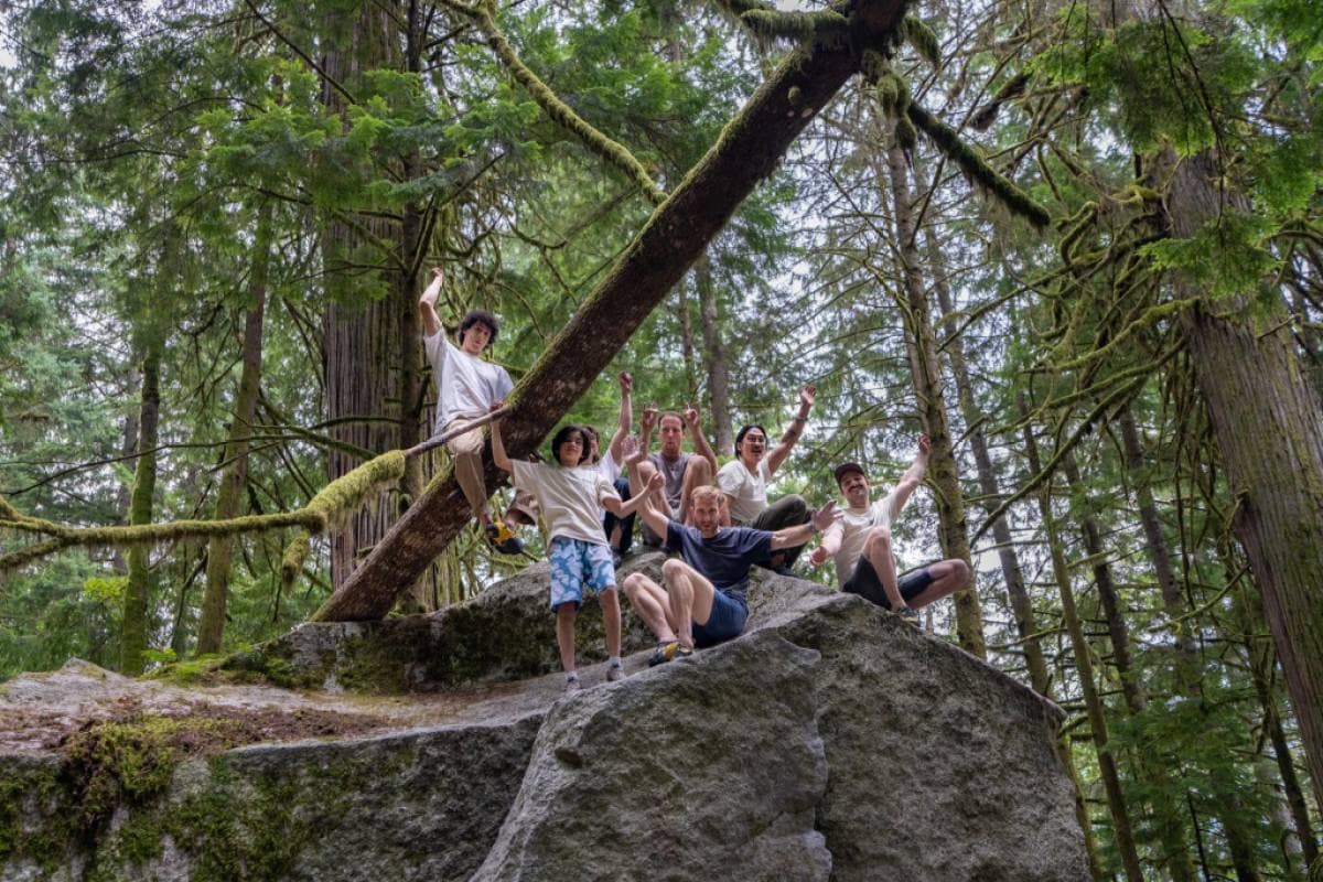 A group of climbers wave hello on top of a large granite boulder