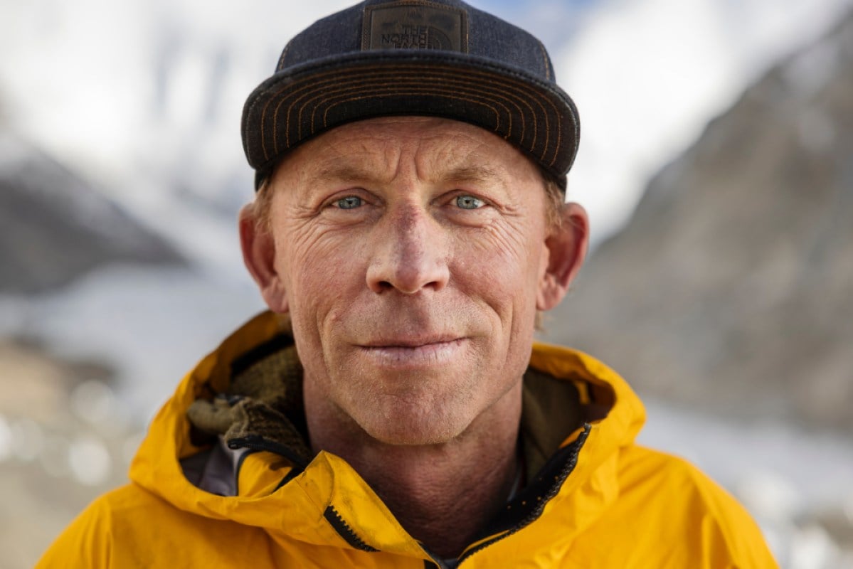A profile of a person wearing a black hat and yellow jacket