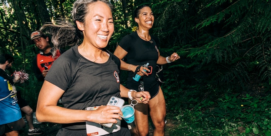 Two women in black t-shirts smiling and running at We Out Here Trail Fest