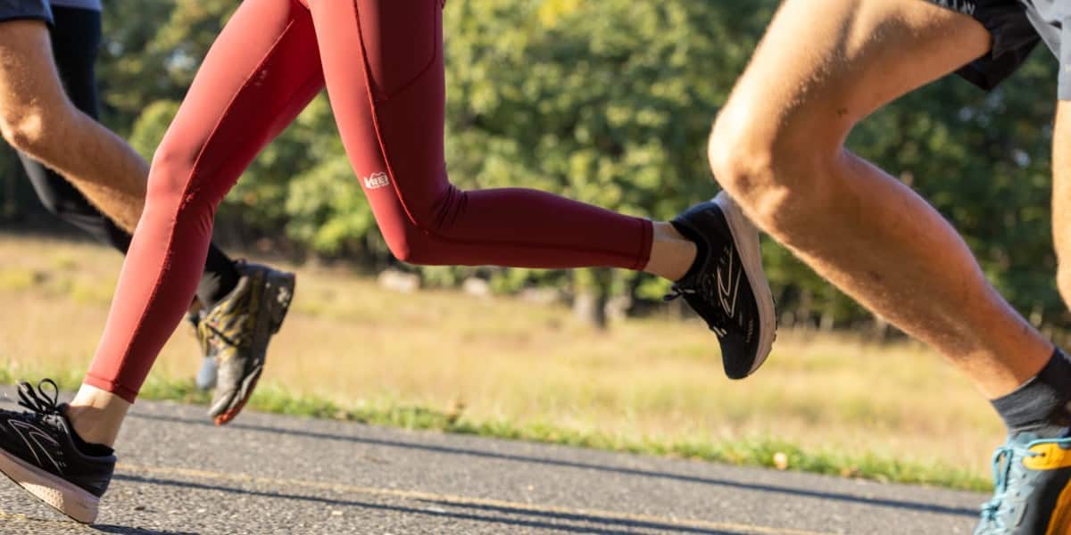 A person running on the road in a red pair of REI-Co-op Swiftland Running Tights.