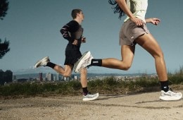 Two people running down a gravel path with a city view behind them.