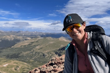 Courtney Conley smiling on a mountain during a hike.