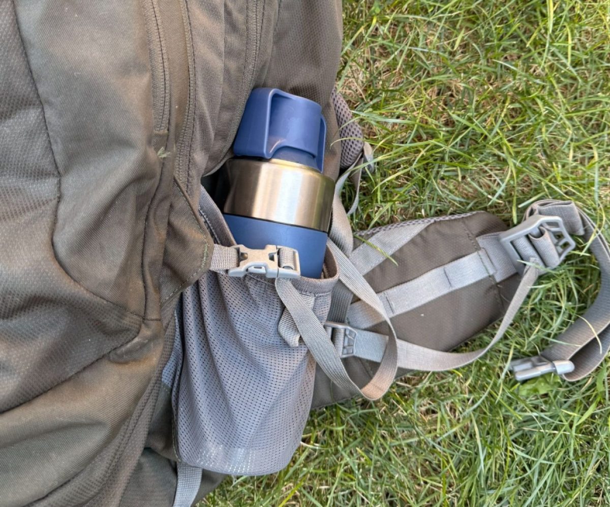 A thermos-size coffee brewer is in the water-bottle holder of a backpack