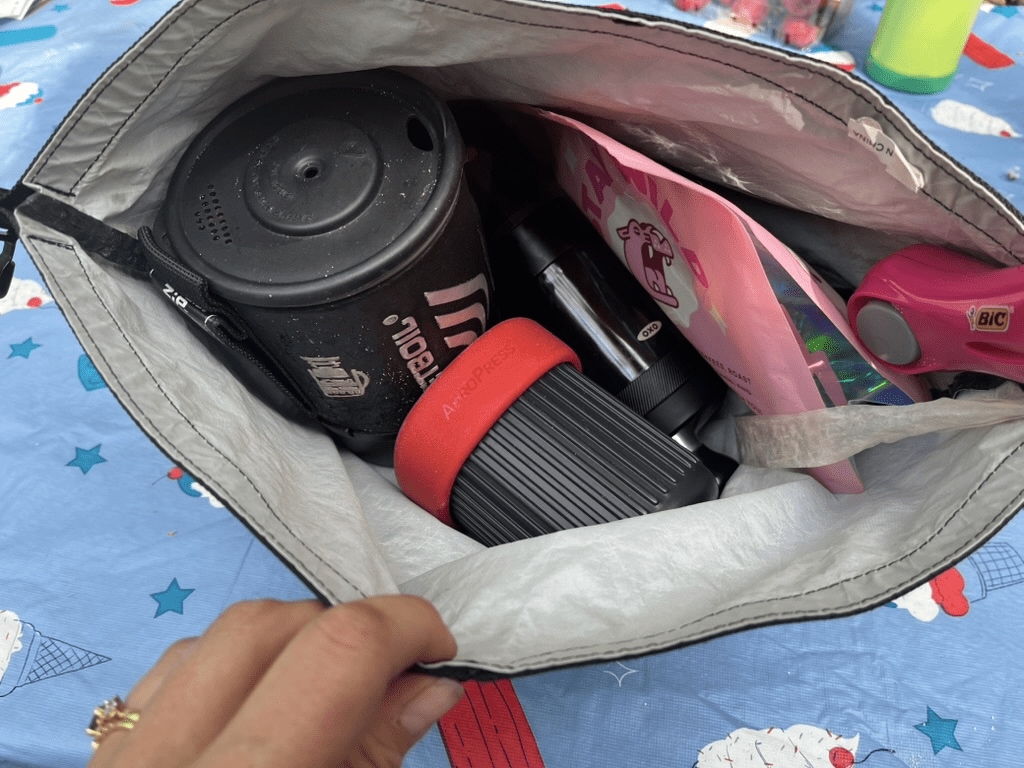 A sac full of different coffee brewing equipment including a Jetboil, AeroPress and OXO gear.