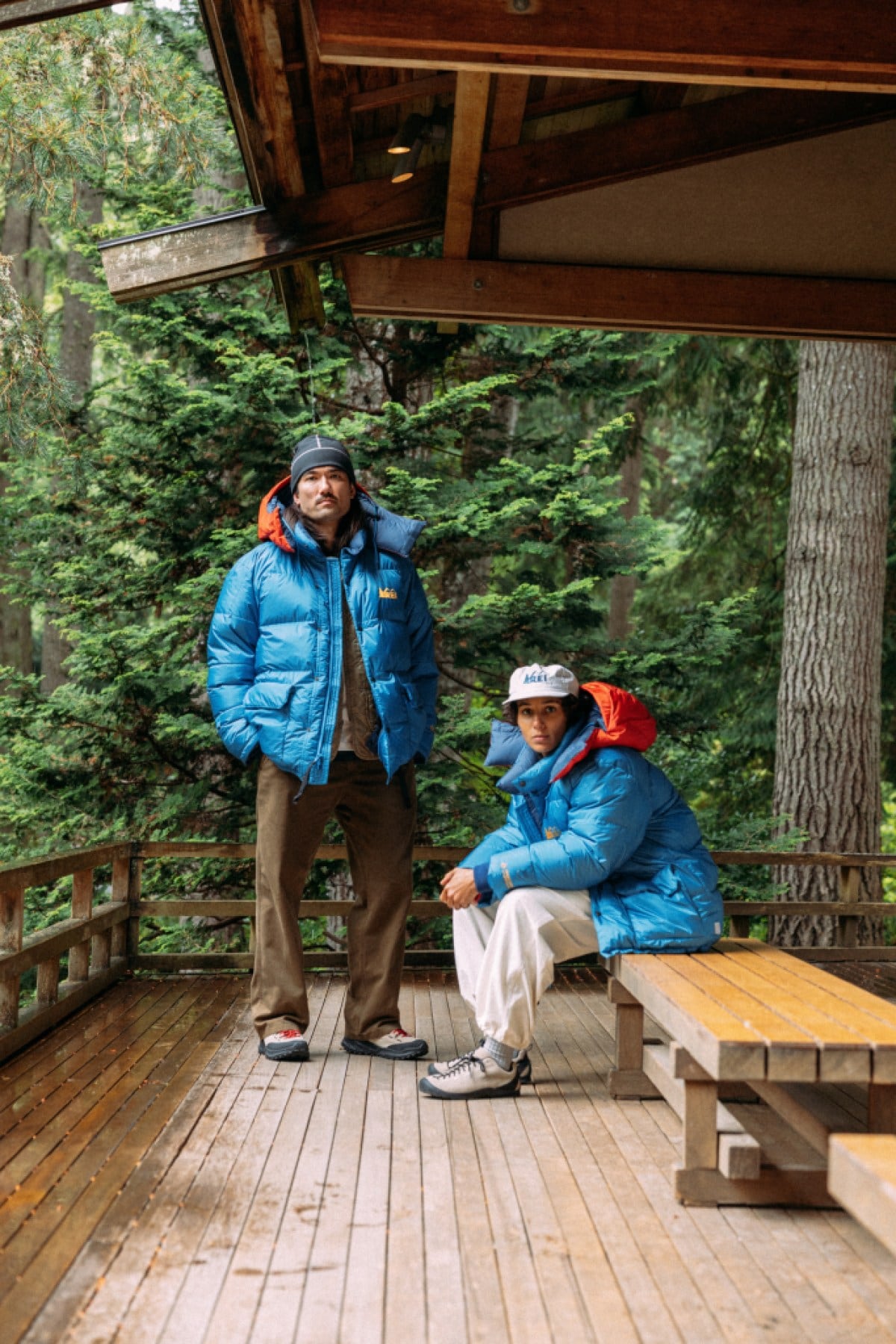 Two people stand outside a building wearing blue parka