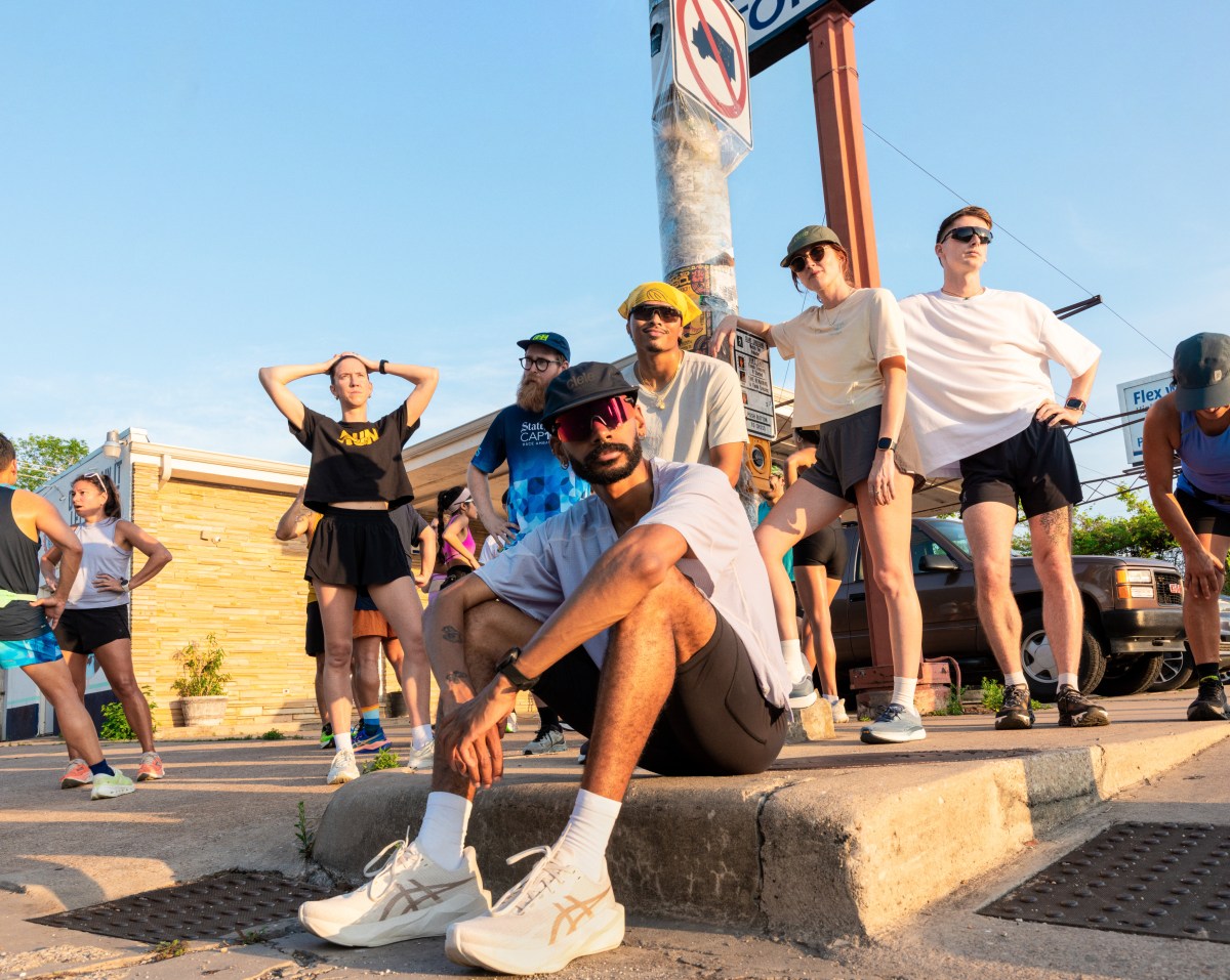 A group of road runners standing and sitting around a stoplight.
