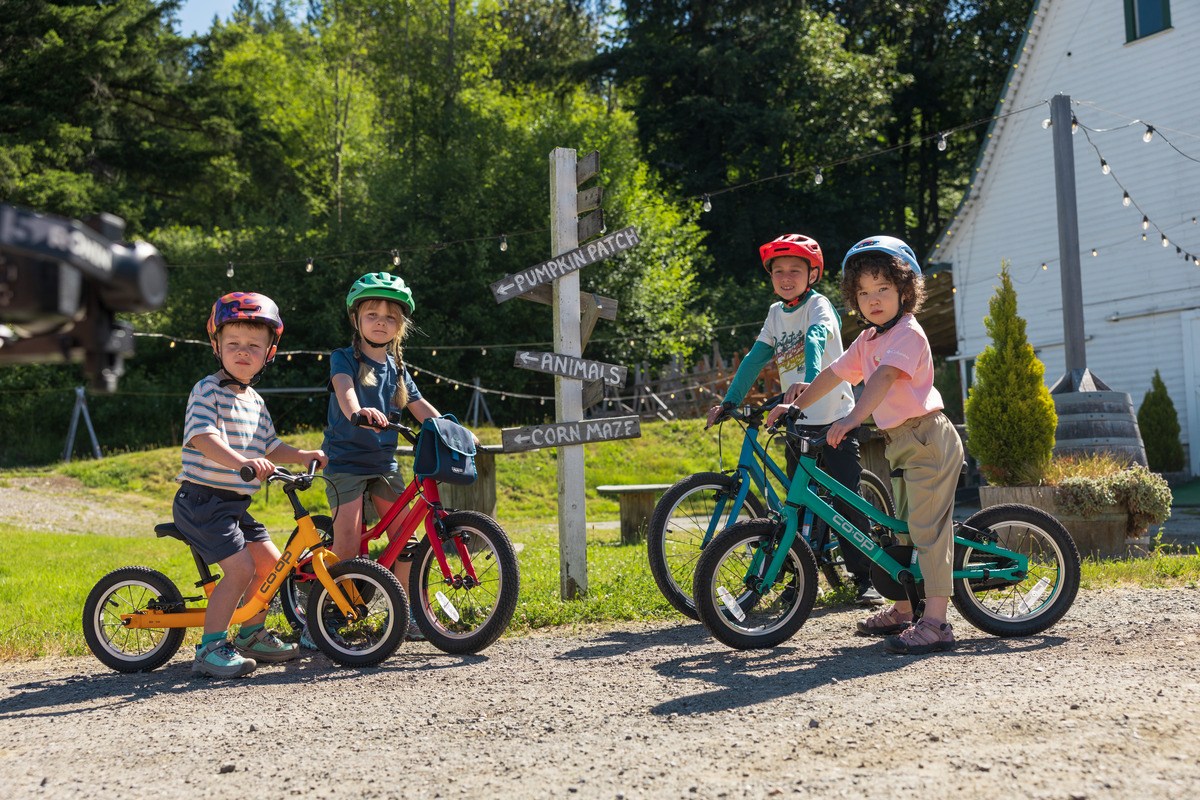 Four kids stand over their Co-op Cycles REV bikes.