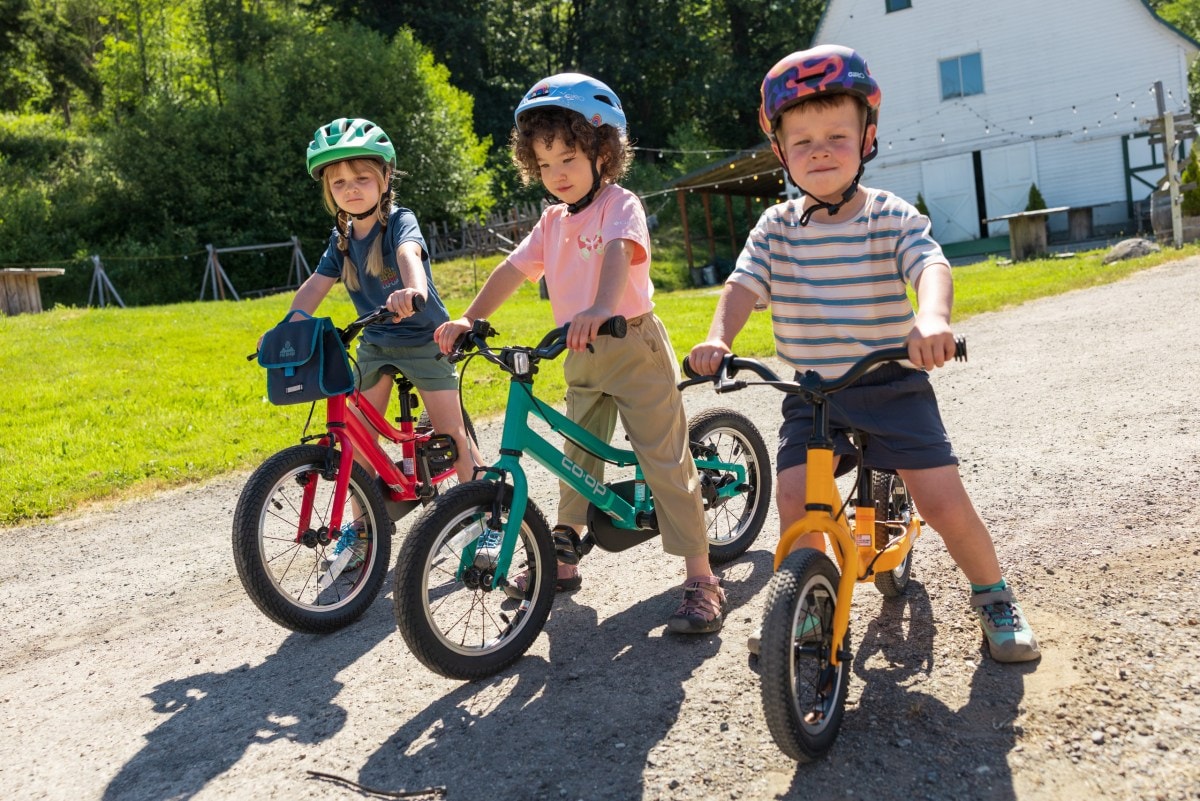 Three kids straddle Co-op Cycles REV bikes.