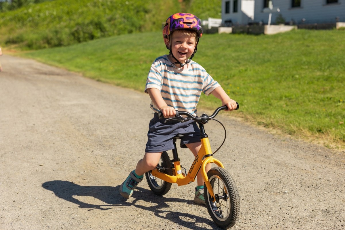 A young child rides the Co-op Cycles REV 12 Kids' Balance Bike