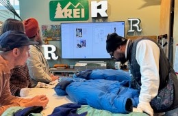 Several people gather around a design table to inspect a 1986 REI Co-op Expedition Parka